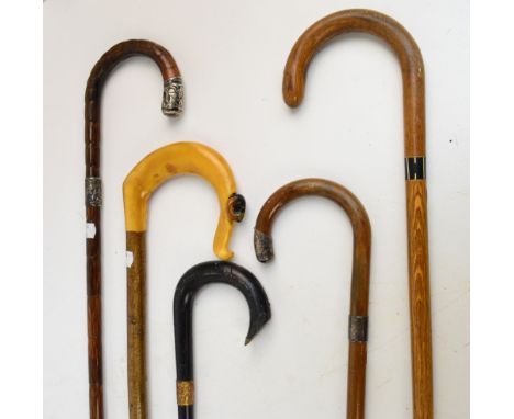 Five canes; a simulated bamboo walking cane with hallmarked silver cap and collar, a further similar example, a crook with ca