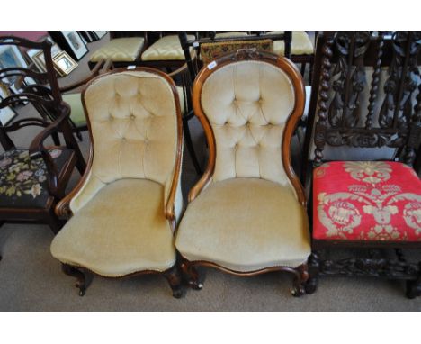 Two Victorian walnut scroll back button upholstered salon chairs, one with carving to curved back, with carved cabriole legs 