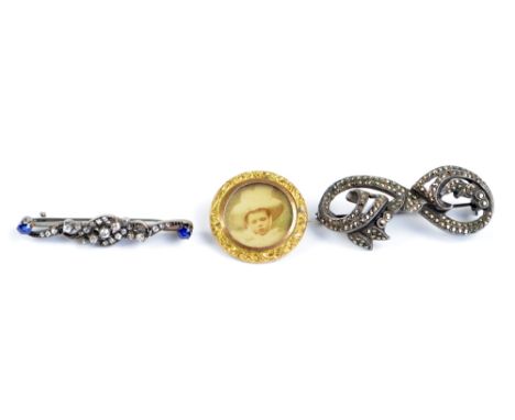 A white metal diamond and sapphire bar brooch of scrolling design, the two sapphires at either end (one small diamond missing