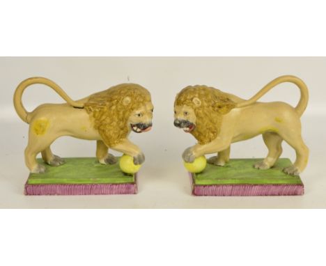 A rare pair of early 19th century Staffordshire Pearl Ware lions, each model on rectangular plinth base with one front paw re