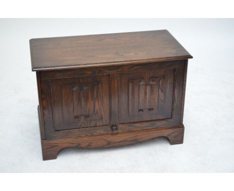 A reproduction oak tv/music cabinet in the form of a coffer, with a linen fold panel up and under door enclosing a sliding sh