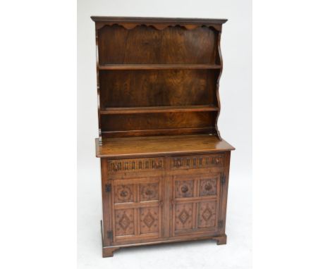 A reproduction carved oak dresser, the plate rack with shaped pelmet and two shelves above two drawers and two quarter panell