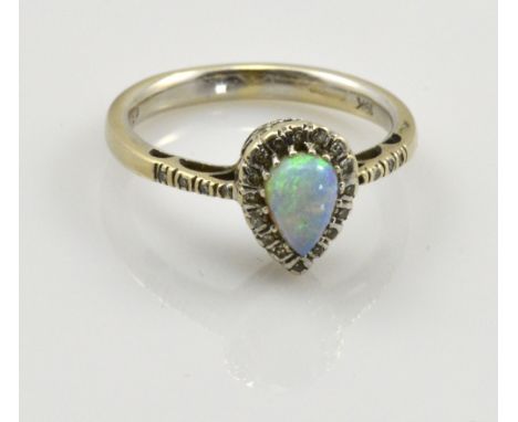 An 18ct white gold opal and diamond ring, the tear shaped central stone surrounded by diamond chips which continue down the s