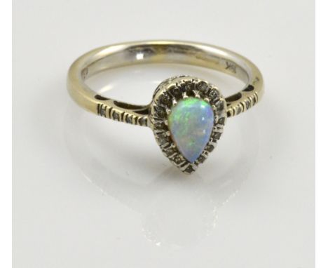 An 18ct white gold opal and diamond ring, the tear shaped central stone surrounded by diamond chips which continue down the s