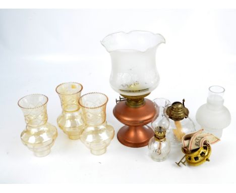 A copper and brass oil lamp with etched shade, two moulded glass oil burners, four additional glass shades, and a spare burne