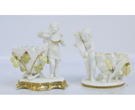 MOORE BROS; two figural gilt heightened bowls, one with an angel holding a drum, height 18cm, the second a cherub holding a c