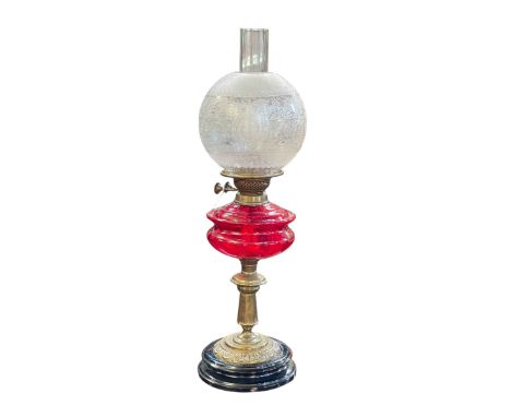 Victorian brass oil lamp with red glass reservoir and etched glass shade.