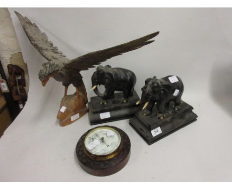 Pair of carved ebony figures of elephants, carved figure of an eagle, circular carved oak aneroid barometer