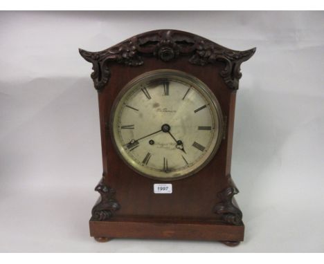 late 19th or early 20th Century mahogany bracket clock with carved applied decoration the circular silvered dial with Roman n