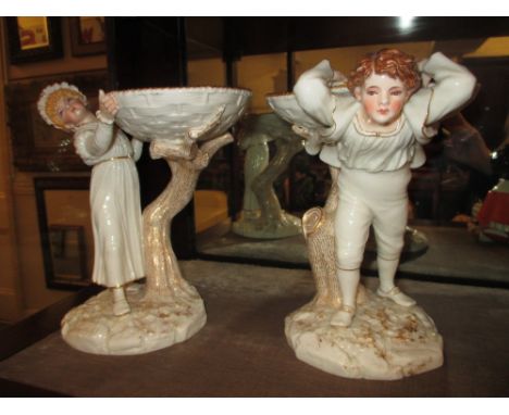Pair of Hadley Worcester figural comports each in the form of a boy and girl beside a tree trunk on a naturalistic base, gree