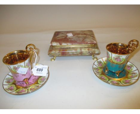 Two floral and gilt decorated cabinet cups with saucers and an onyx jewel box with cover on low gilt claw supports