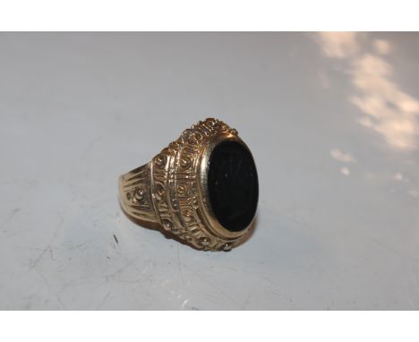 A 9ct gold ring set with black stone having carved profile decoration, ring size S/T, approx. total weight 8gms 