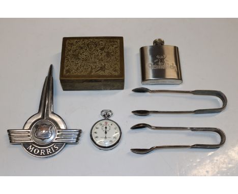 A box containing Morris car badge; two pairs of silver plated sugar tongs; an Eastern brass box; stainless steel hip flask an