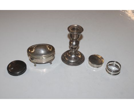 A silver candlestick with filled base; a silver trinket box; a circular silver box; a silver napkin ring and a silver lid (mo