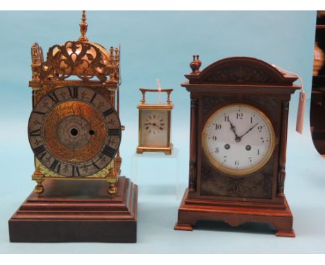 A reproduction brass lantern clock-case, retailer Goldsmiths Co., together with a carved mahogany mantel clock with enamelled