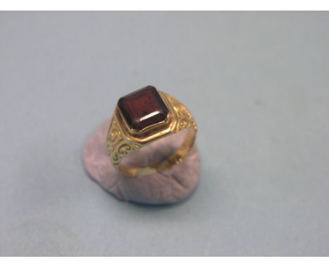 A yellow metal dress ring, with carved shoulders and step-cut garnet, size L/M