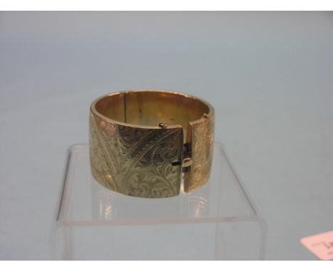 A 9ct. gold bangle, hinged design engraved with foliage throughout, Chester 1902, 60.6 grams