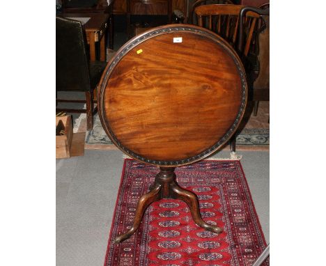 A George III mahogany circular tilt top occasional table with spindle turned gallery, on tripod base, 28" dia