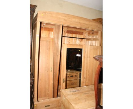 A stripped pine wardrobe fitted centre mirror and two plain panelled doors enclosing hanging space and adjustable shelves, 60