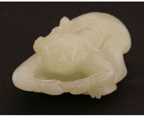 A Chinese jade carving,late Qing dynasty, of a boy lying on his stomach on a lotus leaf, a lotus flower besides him, the ston