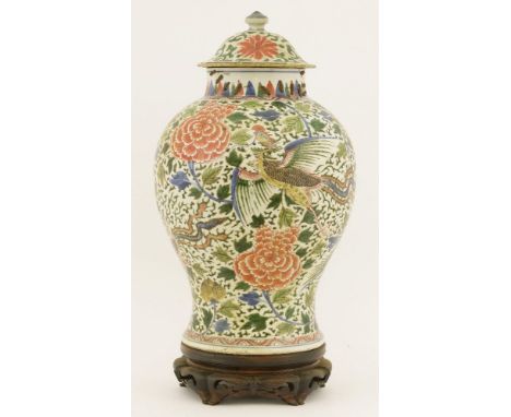 A Chinese wucai vase and cover,Kangxi (1662-1722), of baluster form, painted with a phoenix amongst scrolling peony, the dome