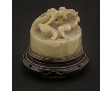 A Chinese jade seal, 20th century, of circular form, carved with a dragon crouching on top, the base with archaic characters,