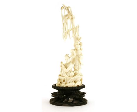 A Chinese ivory carving,late 19th century, with Han Xiangzi playing his flute, He Xiangu carrying a bouquet of lotus on her s