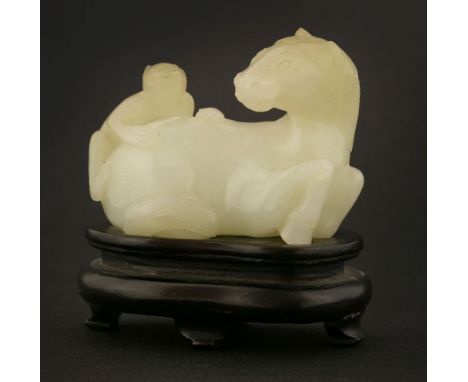 A Chinese jade carving,late Qing dynasty, of a recumbent horse, turning its head to look at the monkey on his back, its hair 