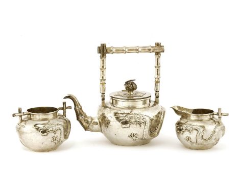 A Chinese silver tea set,late 19th century, comprising:a teapot,a milk jug, anda sugar bowl,decorated with dragons in relief,