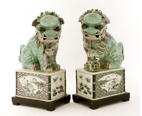 A pair of Chinese famille verte Buddhist lions,possibly Kangxi (1662-1722), one with his left paw on a ball, the other with a