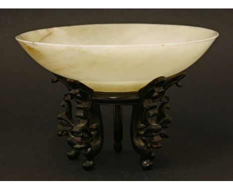 A Chinese jade dish,Qing dynasty (1644-1911), of circular form on a circular base, the stone of pale white tone with inclusio