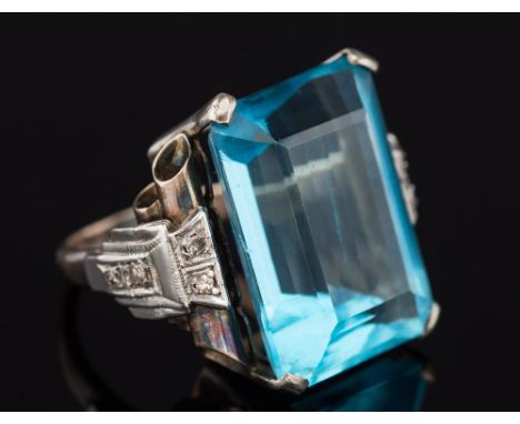 An art deco-style white metal, blue glass and diamond mounted dress ring: with large rectangular blue glass centre-stone betw