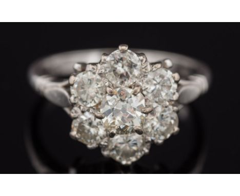An 18ct white gold and diamond mounted circular cluster ring: with central round old brilliant-cut stone claw-set within a su