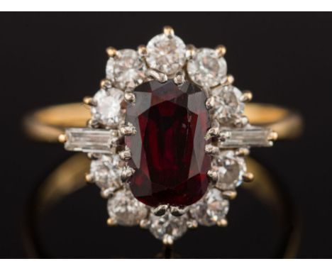 An 18ct gold, ruby and diamond oval cluster ring: with central oblong ruby 8.5mm long x 6mm wide x 4.2mm deep, estimated to w