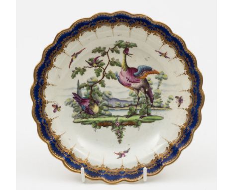 A Worcester dessert plate: with scalloped edge, painted with a vignette of fancy birds in a romantic landscape within a gilde
