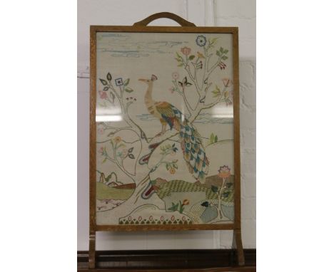 An oak firescreen with needlework insert depicting a peacock.