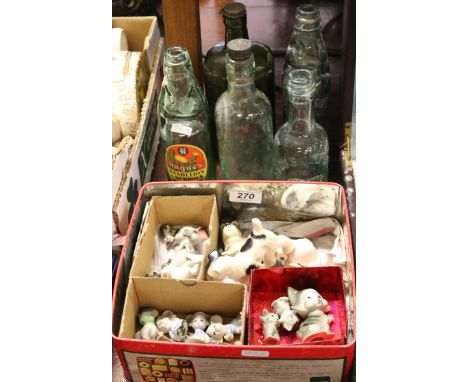 A tin of ceramic animal ornaments dogs, cats and mice along with five advertising bottles.