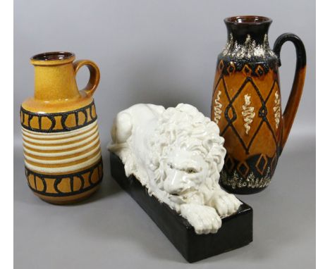 A ceramic model of a lion on a plinth along with two West German pottery vases.