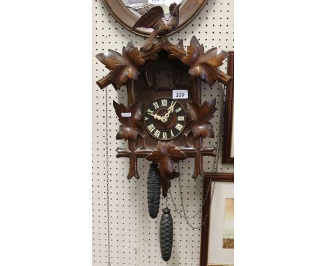 A Black Forest twin weight cuckoo clock adorned with carved acanthus leaves and a wood pigeon pediment.