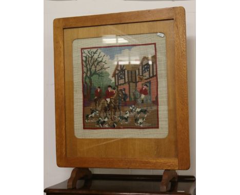An oak firescreen with woolwork tapestry insert depicting a hunting scene.