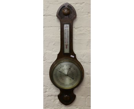 A carved oak banjo barometer with silvered dial and thermometer.