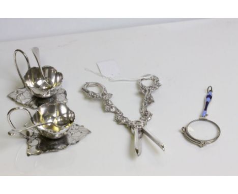 A pair of EPNS cruets, the bowl in the form of a flower sat on a leaf, with spoons, together with a pair of white metal grape
