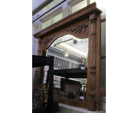 A carved light oak framed arch topped over mantel mirror with grape and vine and half column. 87cm x 108cm