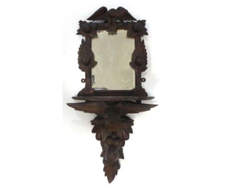 A Black Forest-type carved wall mirror with a shelf and figural support, h. 94 cm