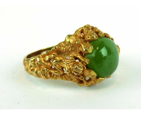 A yellow metal ring set circular cabochon jade within a figural carved mount,ring size Z,9.7 gms