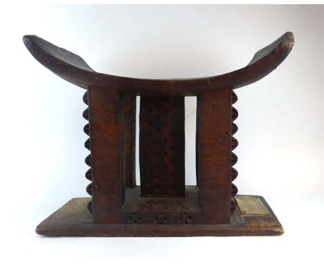 Ethnographica: an Ashanti stool, the curved seat over a pierced central column and four supports with carved side panels on a