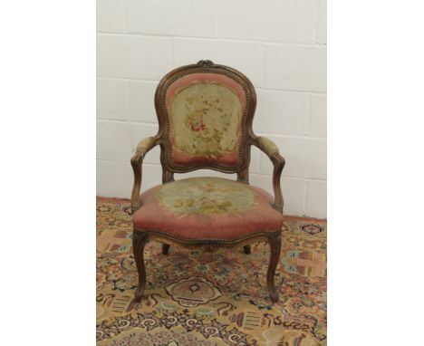 19th century French walnut fauteuil with floral tapestry cartouche-shaped pad back and seat and swept arms, raised on cabriol