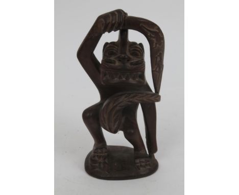 Oceanic hardwood 'Tiki' carving depicting a devil with throwing stick, standing upon a human, on shaped base, 23cm high