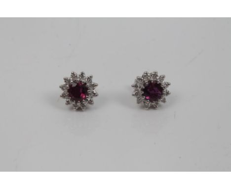 Pair ruby and diamond flower-head cluster earrings, each centred with a round mixed cut ruby surrounded by twelve brilliant c