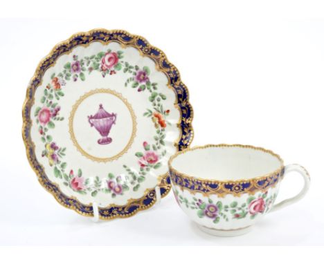 18th century Worcester fluted tea cup and saucer, polychrome painted with urns and floral garlands within gilt and blue borde